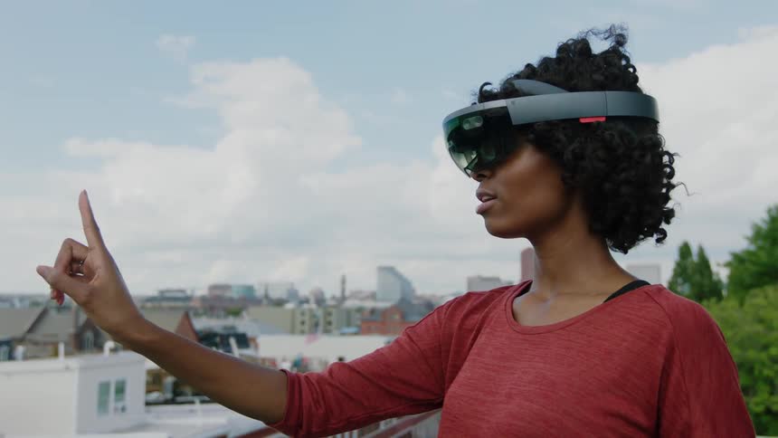 Woman holding her index finger in front of her while wearing virtual reality headgear outside on a cloudy day