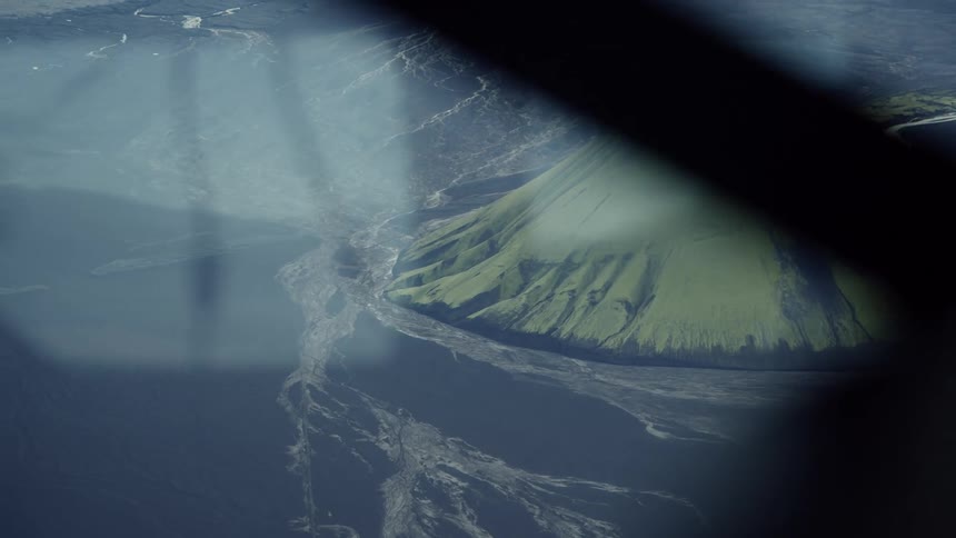 Volcanic island with green slopes and erosion lines surrounded by deep ocean