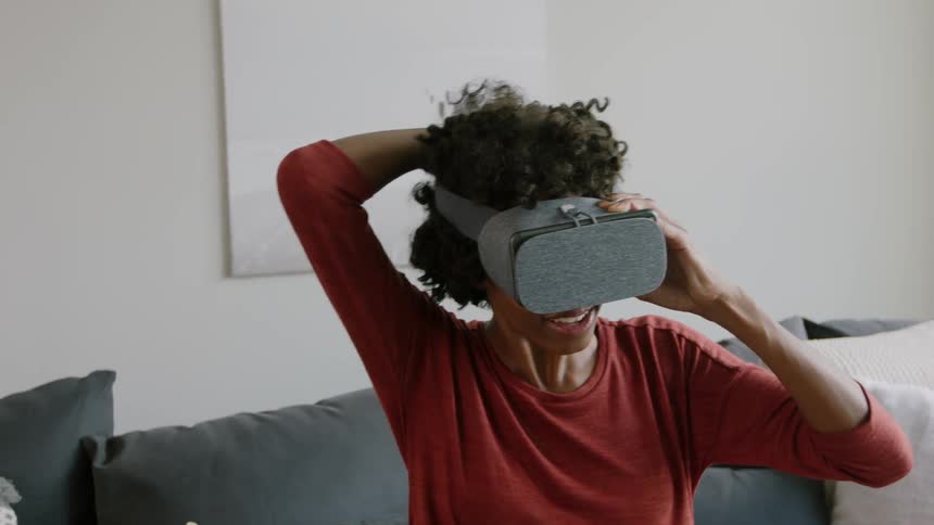 A woman puts on a vr headset while sitting down