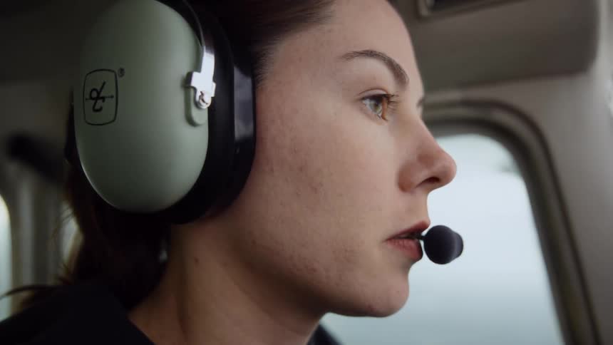 Woman pilot speaks into her microphone as she flies a small airplane