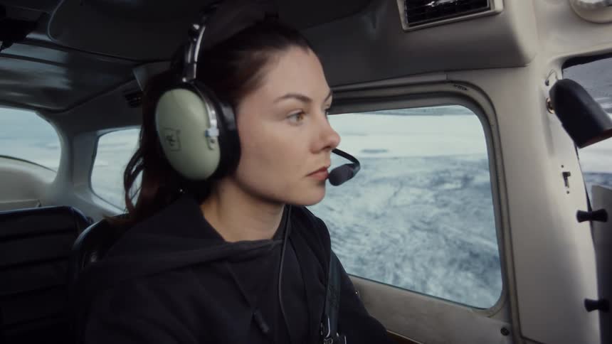 Woman pilot flying a small airplane as she looks out the window