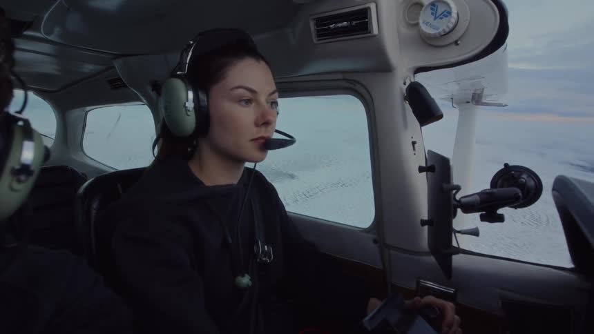 A woman flying a plane with a headset on