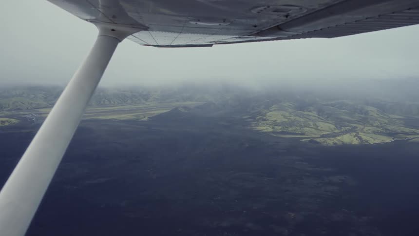 The plane flies high above the clouds over the landscape