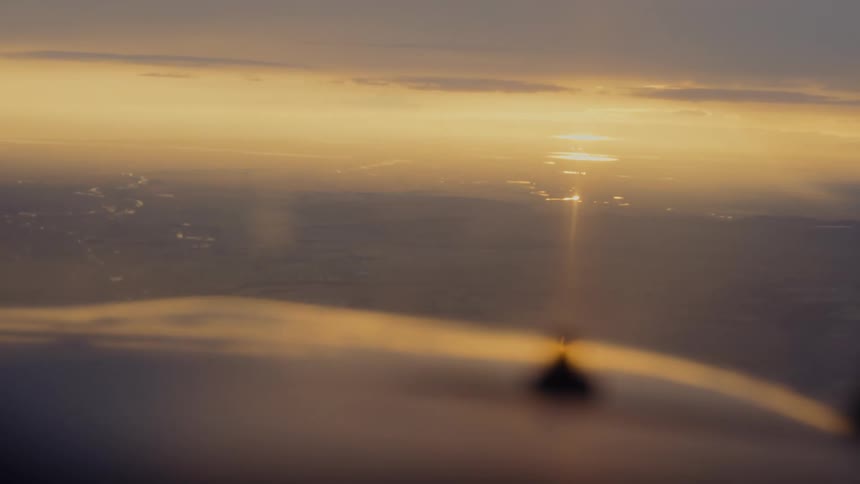 Golden sunset reflection on aircraft surface with winding river and clouds in the background