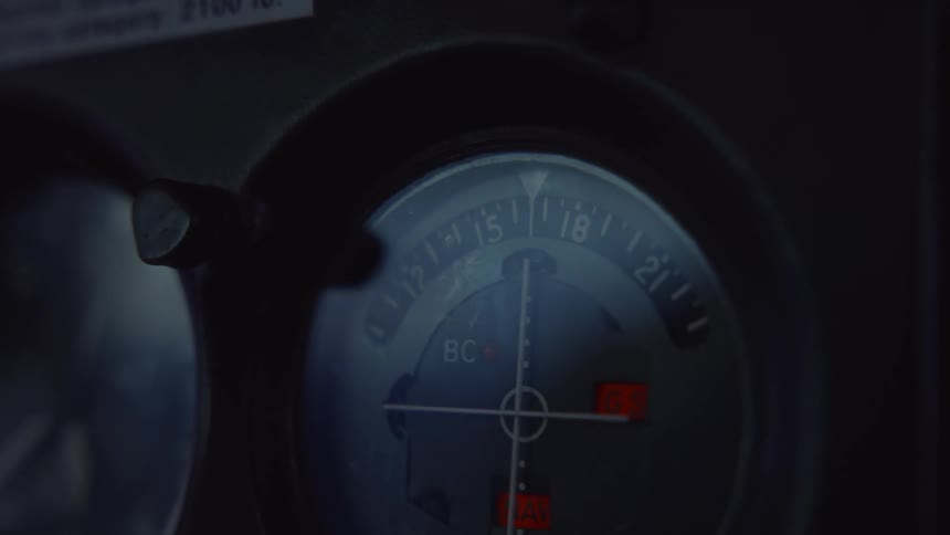 Circular navigation instrument displays directional markings and illuminated indicators on a dark panel