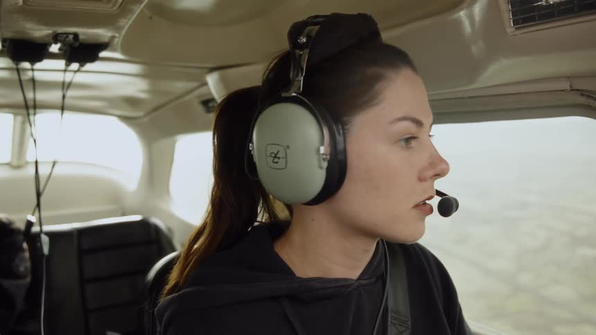Person with headset operating communication in light aircraft cockpit during flight