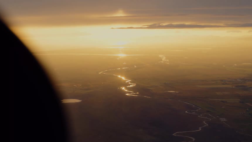 Winding river reflecting sunset light seen from high altitude