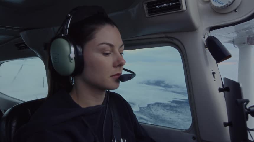 The woman looks around while flying over the snow