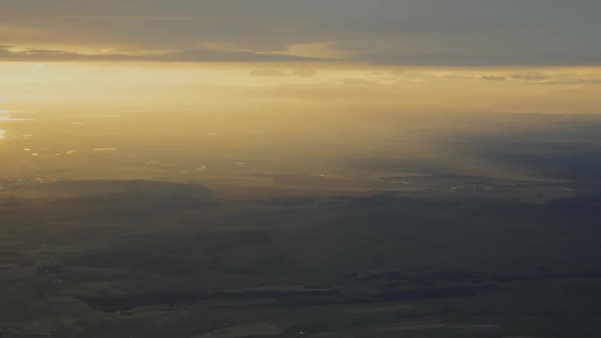 An orange sunset stretches across the horizon the sky glowing warmly above a wide expanse of open land that fades into the distance