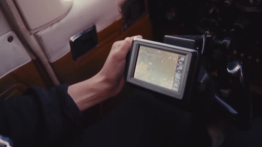 Hand gripping yoke with digital screen showing navigation data and speed inside aircraft cockpit