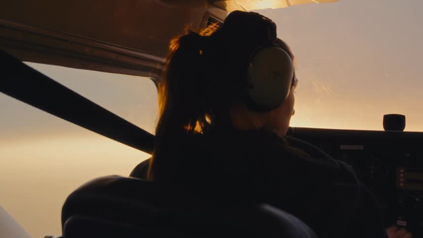 Pilot wears a headset inside an aircraft during flight at sunset