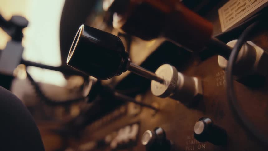 Hand adjusts a metal knob on an analog panel with technical markings in an industrial setting