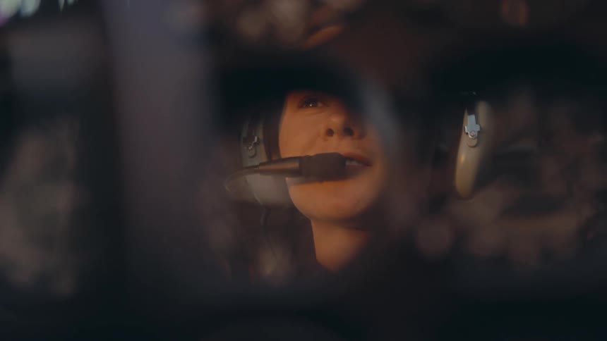Pilot looks toward the aircraft instruments while wearing a helmet and oxygen mask inside the cockpit