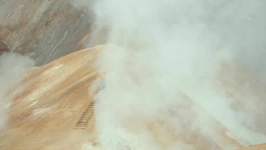 A view of a mountain with steam and clouds above it