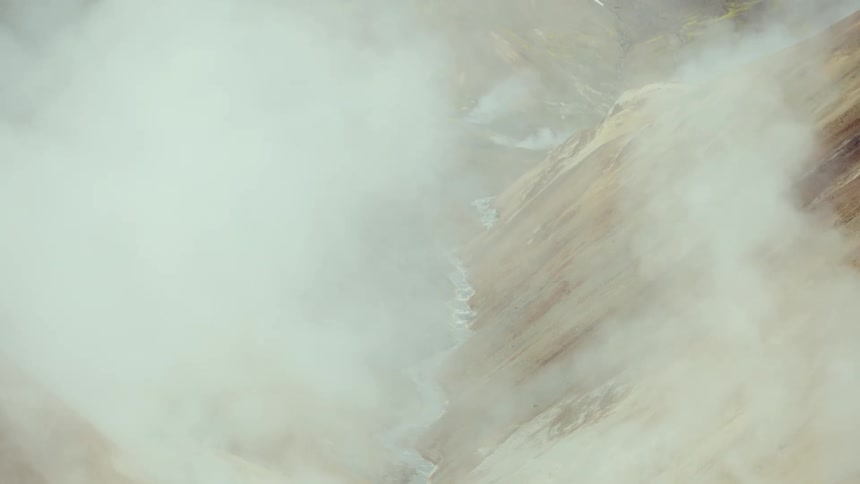 Geothermal area with rising steam and mineralcolored ground in volcanic region