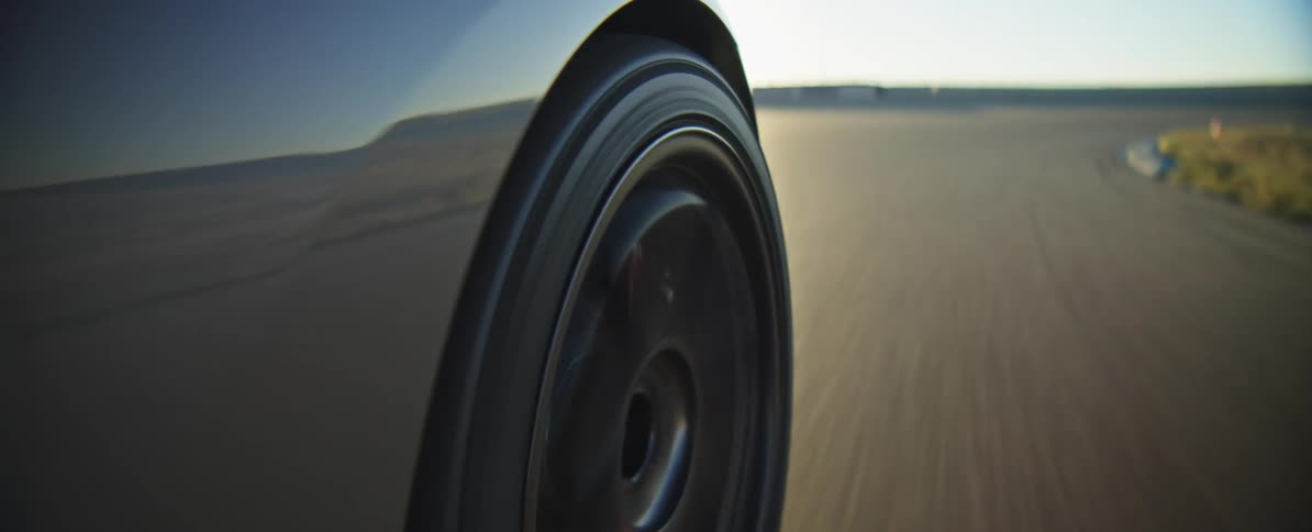 Car tire spins as it travels on a road moving around a curve