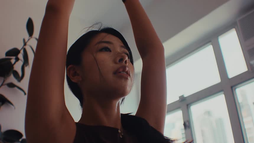 A young woman practices yoga indoors at midday the light coming in clean and bright through the windows she moves into a stretch with steady focus her posture calm and controlled as the quiet room holds a soft midday stillness