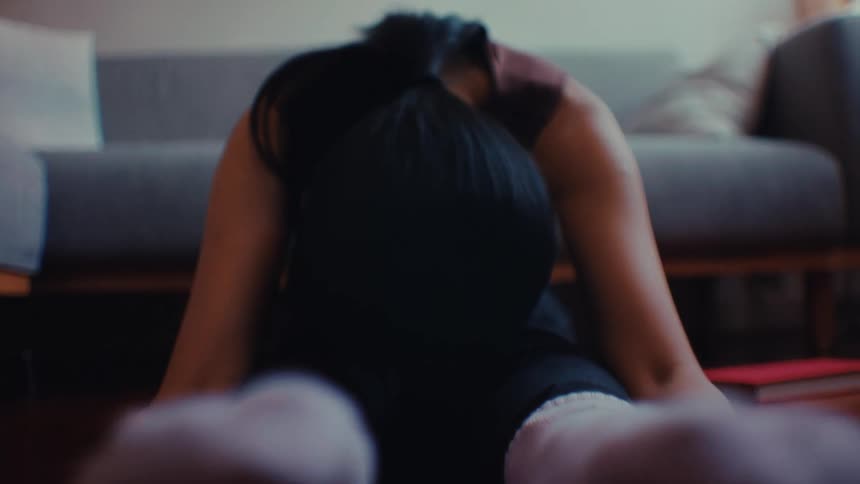 A woman seated on the floor leans forward and stretches with her feet outwards