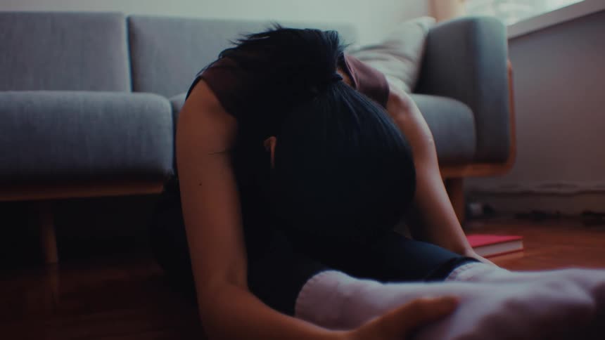 Woman performs seated stretching exercises with arms extended in a brightly lit room
