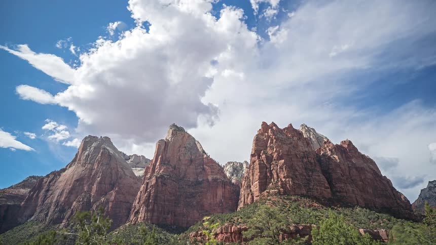 White clouds move over a mountain rock formation in the wilderness at midday