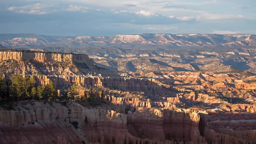 Spiralshaped rock formations rise up in bryce canyon under a partly cloudy sky