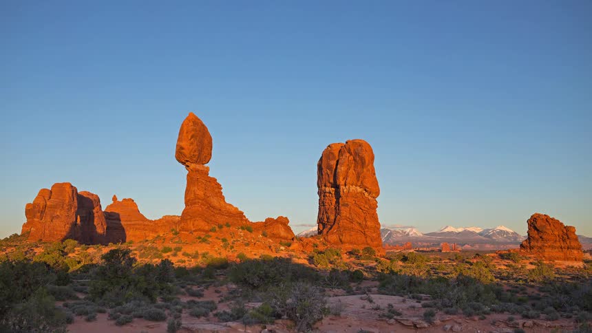 People walk in the desert with mesa and butte red rock formations across the landscape