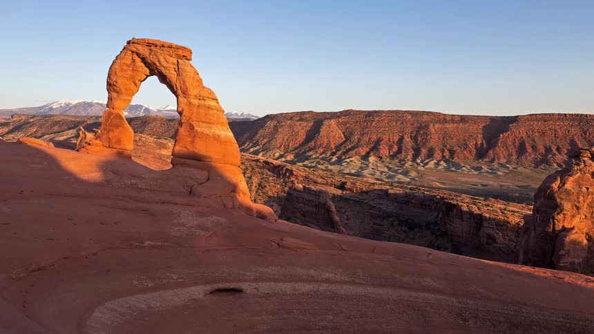 Sandstone arch stands out in delicate arch with snowcapped mountains in the background