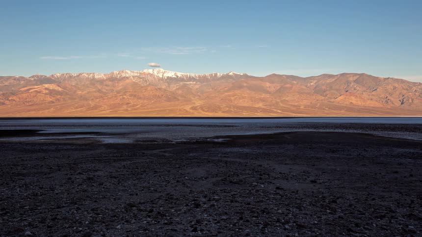 Arid desert with a salt flat and snowcapped mountains in the background