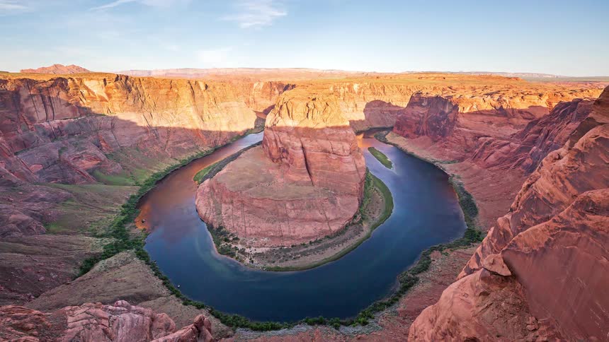 Colorado river bends around a rock formation at horseshoe bend during sunset
