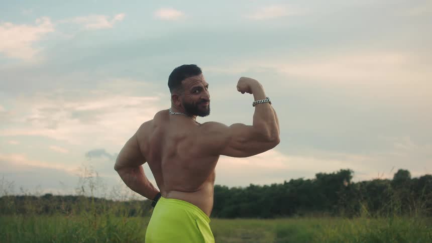The man flexes his muscles on the field