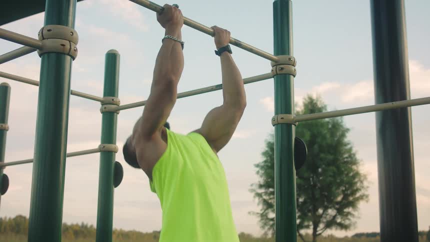 Man performs a pullup exercise on an outdoor fitness structure