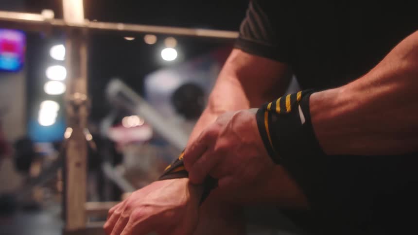 Person adjusting training wrist wraps in a gym environment