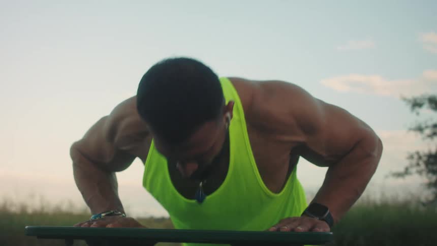 The man is doing push ups on the grass