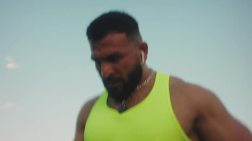 Muscular man jogging lightly along a trail in an open area with vegetation