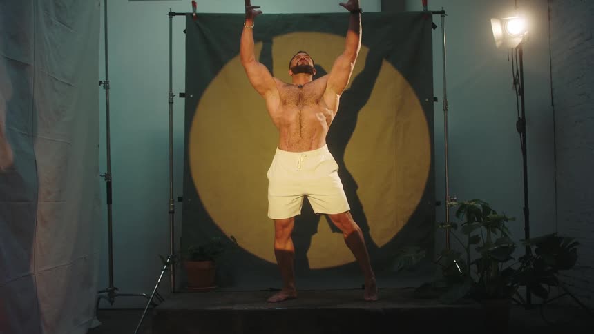 Muscular individual strikes a bodybuilding pose with shadow cast on a circular illuminated background