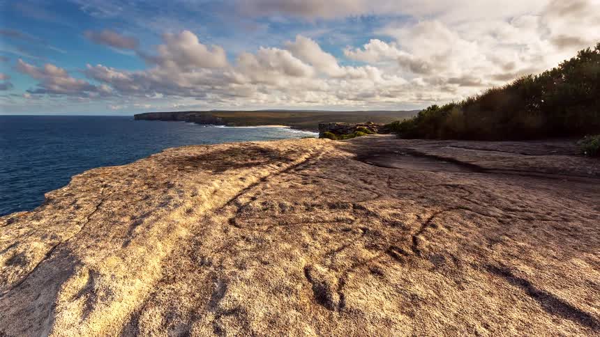 Rocky platform by the ocean with an extended coastline and a partly cloudy sky
