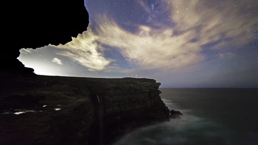 Stars fill the sky above the cave