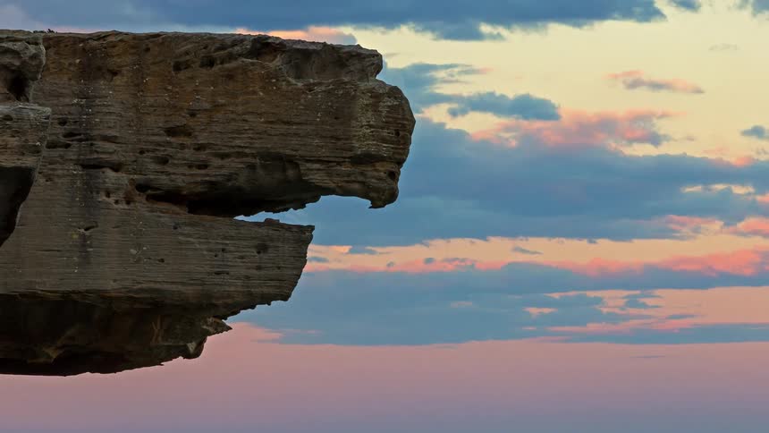 Rocky outcrop juts over the ocean beneath a cloudfilled evening sky