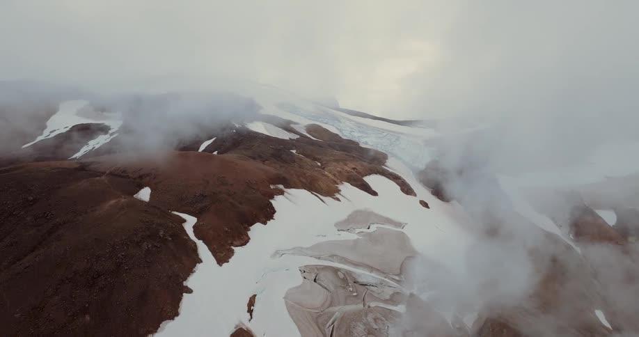 Mountainous landscape with snowcovered areas partially obscured by low clouds