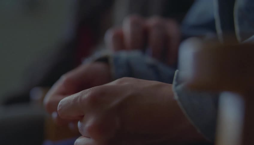 Closeup of hands clasped together showing a quiet moment of support and care