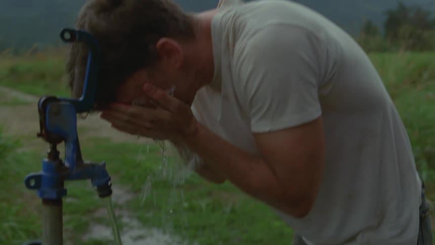 Man washing his face at an outdoor tap with running water