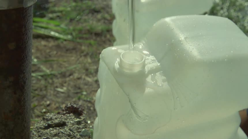 Man filling a gallon of water and washing his face