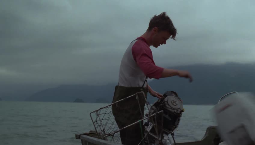 Man on a boat removing a fishing equipment box over the sea