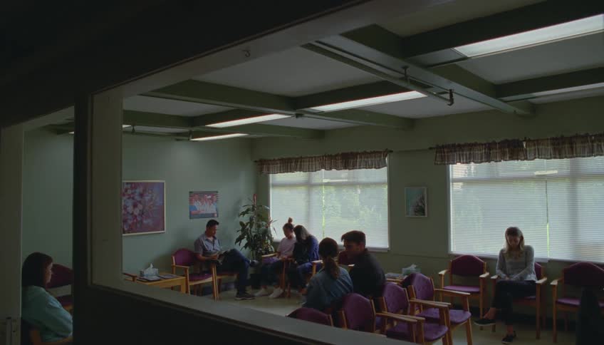 A group of people sit in a lobby at midday waiting quietly for their appointments