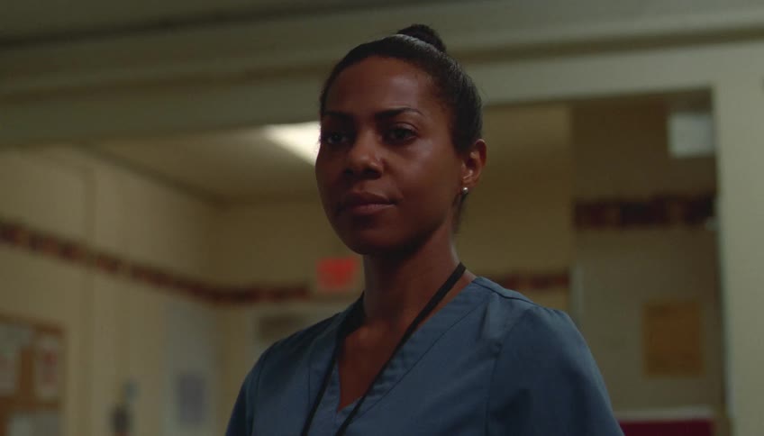 Young adult female black nurse walking into a room with a smile and then looking worried indoors during day time