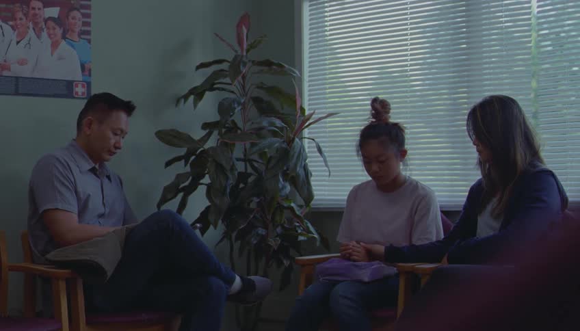 People seated in a counseling room with hands joined in an indoor setting