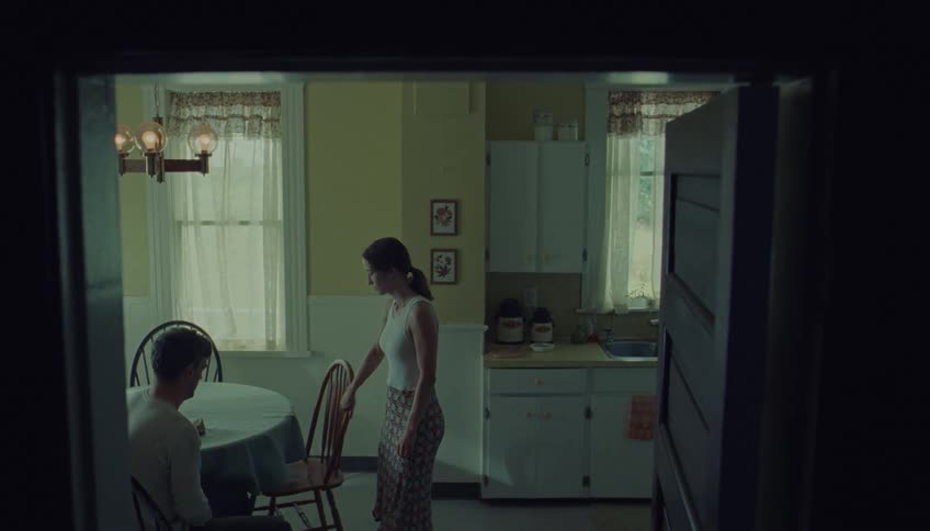 Upset couple sits across from each other at a kitchen table in a tense quiet moment indoors