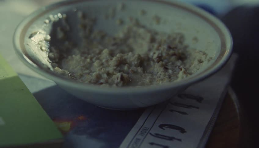 A person is outside eating a bowl of oatmeal
