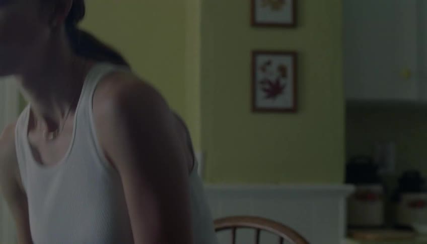 The woman walks into the room and sits on the chair