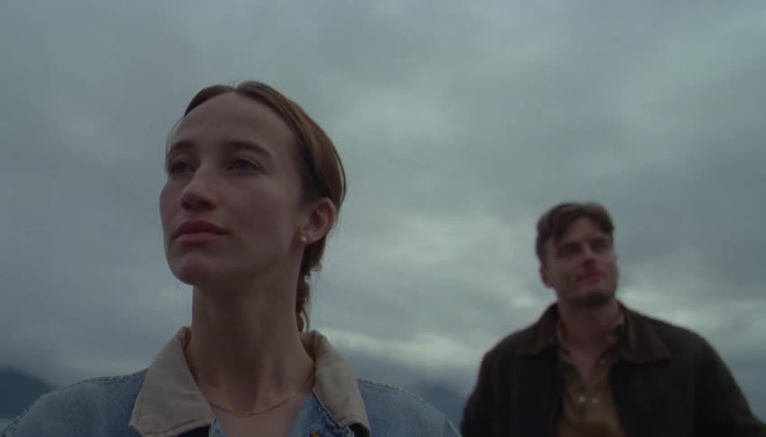 A man and woman ride on a boat under a very cloudy sky